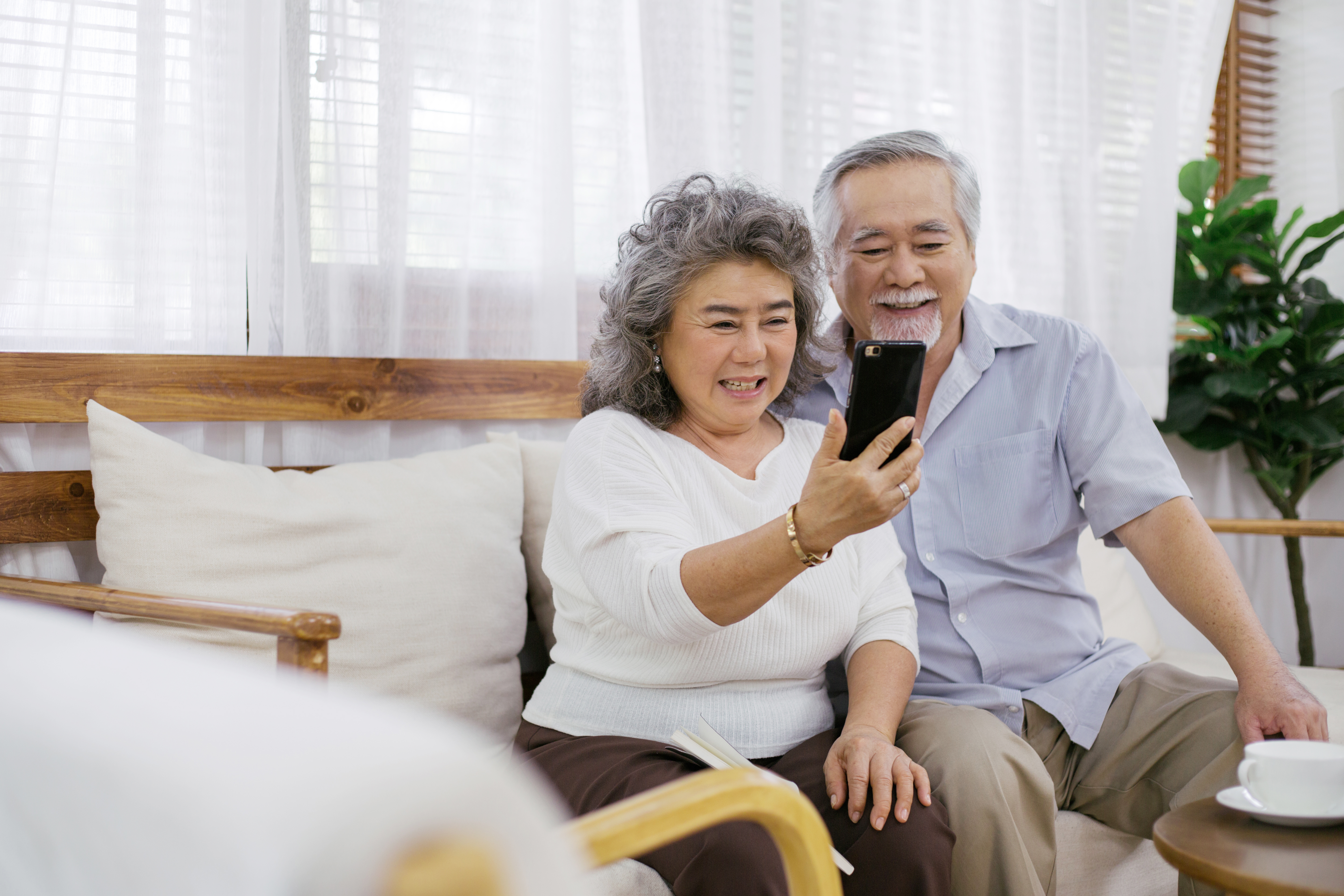 elderly couple sitting on the couch taking a selfie